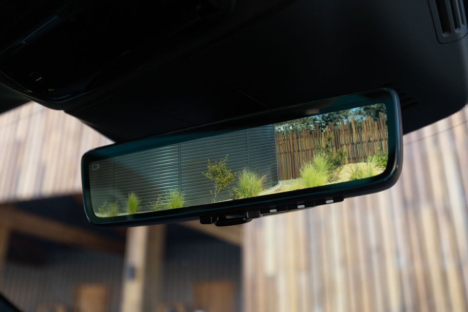 Digital rear-view camera mirror in the 2027 Polestar 5 Performance showing a garden and timber fence behind the car
