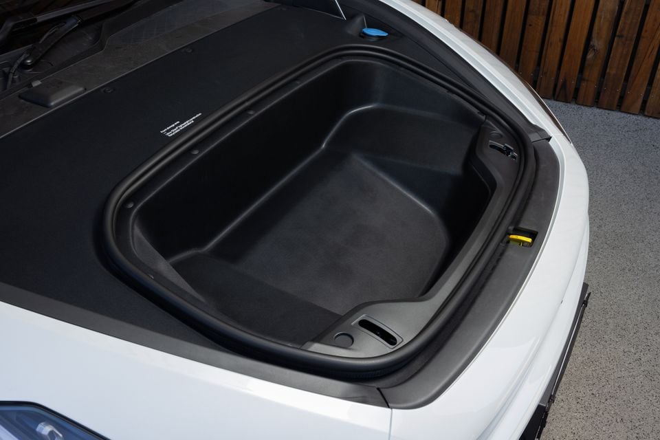 Open front storage compartment, or frunk, of a white 2027 Polestar 5 Performance with a black moulded liner