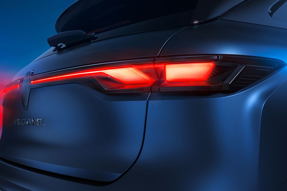 Close-up of the illuminated red LED tail-light on a 2027 Renault Megane E-Tech, with the Renault diamond badge and Megane lettering on the tailgate