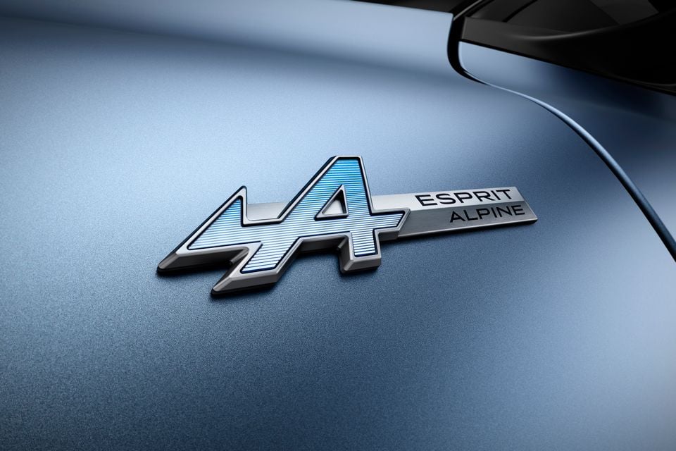 Close-up of the Alpine 'A' Esprit Alpine badge on the blue-grey bodywork of a 2027 Renault Megane E-Tech