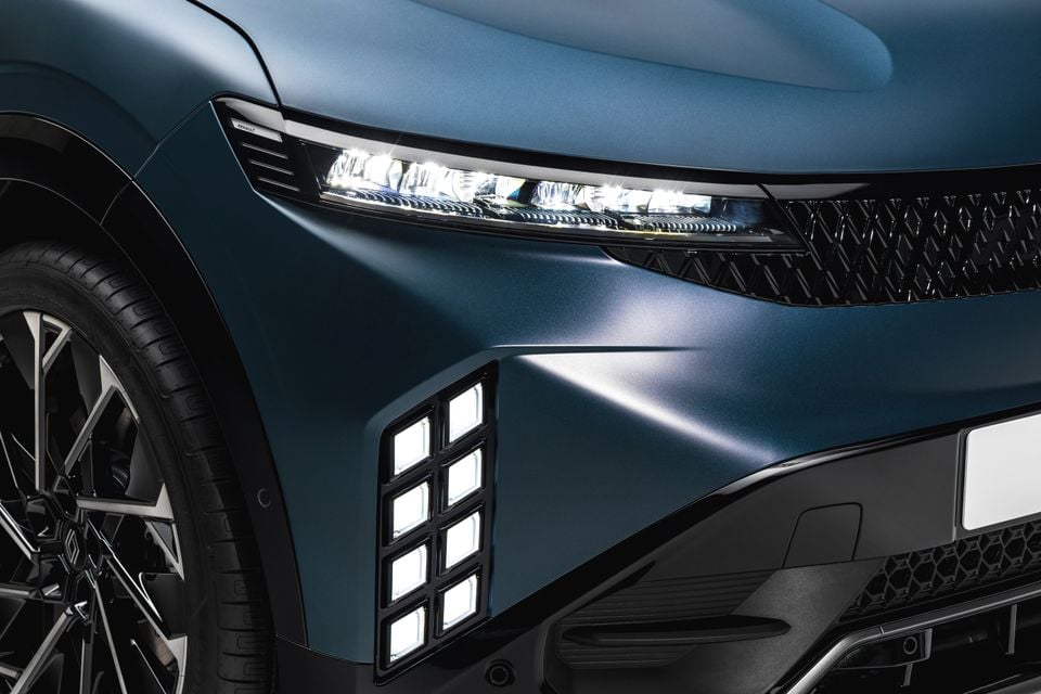 Close-up of the LED headlight, grille and front corner of a blue 2027 Renault Megane E-Tech Esprit Alpine