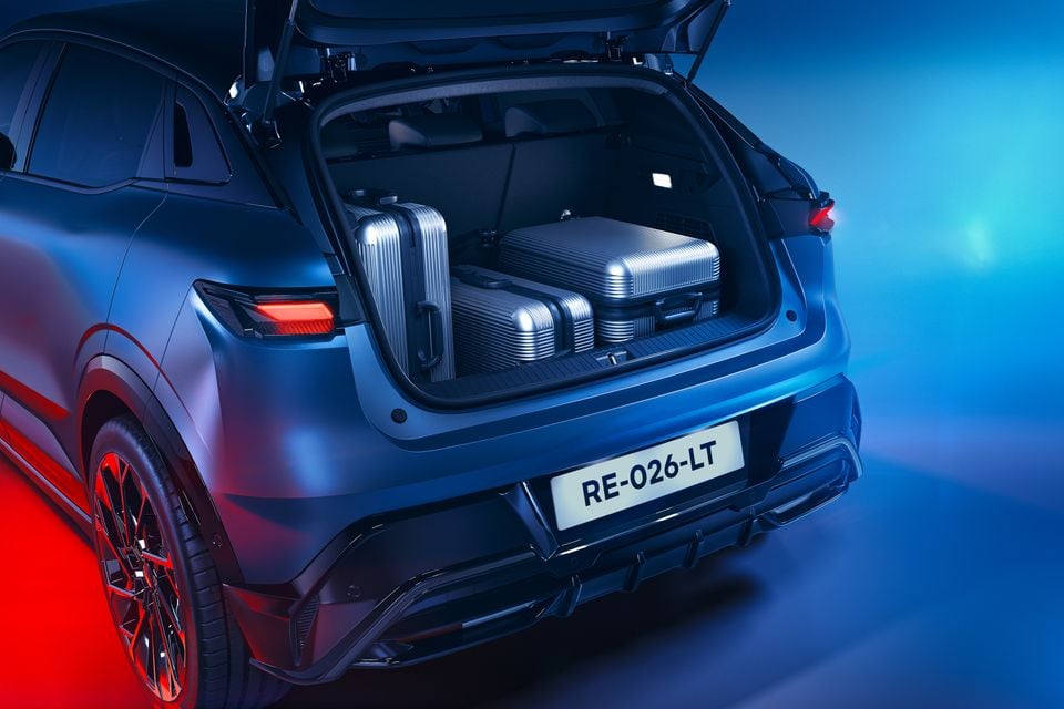 Open boot of a dark blue 2027 Renault Megane E-Tech Esprit Alpine holding three silver suitcases, seen from the rear in a studio