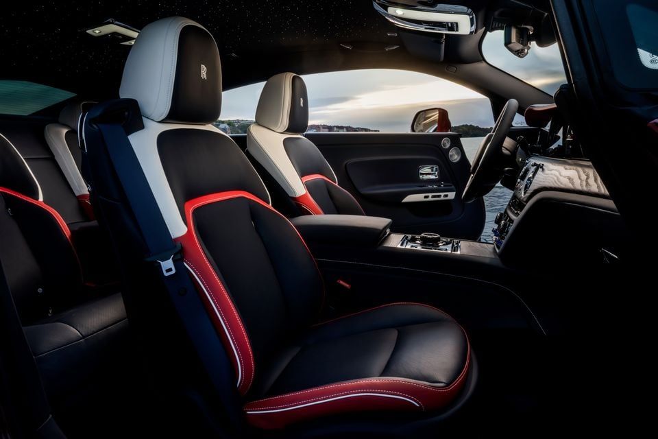 Black, white and red leather front seats inside the 2027 Rolls-Royce Spectre, with starlight headliner and rear seats visible