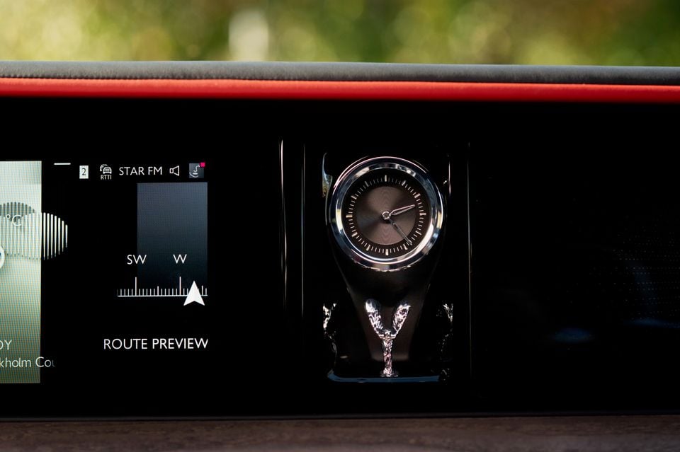 Dashboard of the 2027 Rolls-Royce Spectre showing an analogue clock with a Spirit of Ecstasy figurine beside the infotainment screen