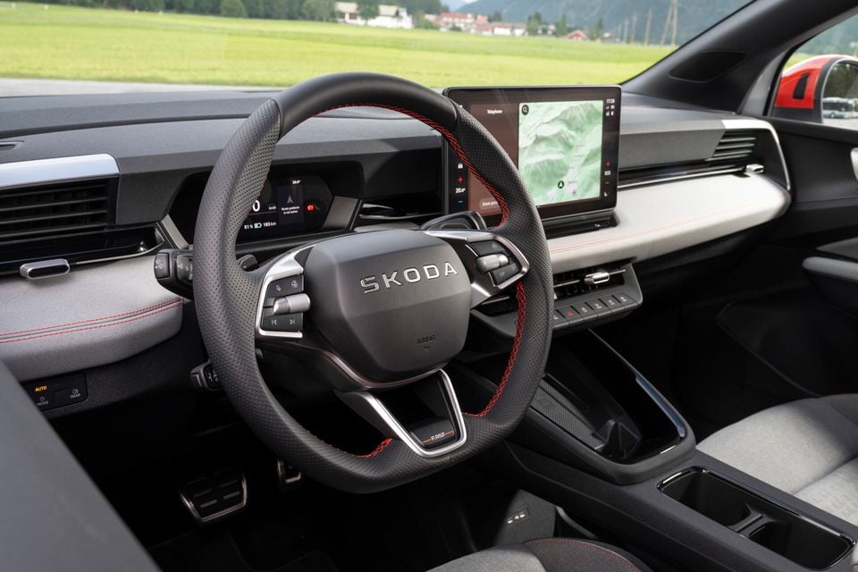 Interior of a Skoda Epiq First Edition showing the flat-bottomed steering wheel with red stitching and Skoda logo, digital instrument cluster, and central touchscreen displaying navigation.