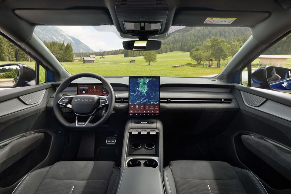 Interior of a Skoda Elroq showing the dashboard, large central touchscreen displaying a map, digital instrument cluster, steering wheel with Skoda logo, and front seats