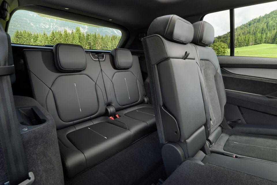 The third-row seats of a Skoda Peaq, trimmed in dark leather with contrast stitching, viewed from the second row with a scenic landscape visible through the rear windows.
