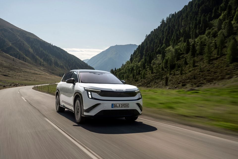 A white Skoda Peaq SUV driving on a mountain road, seen from the front