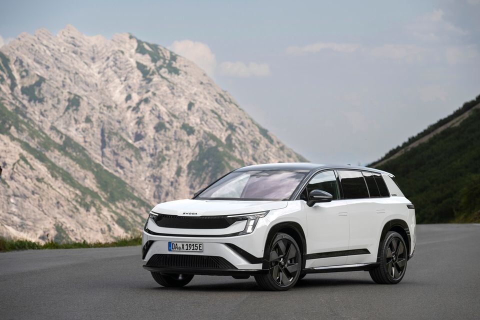 A white Skoda Peaq SUV seen from the front-side angle, parked on a mountain road with rocky peaks in the background