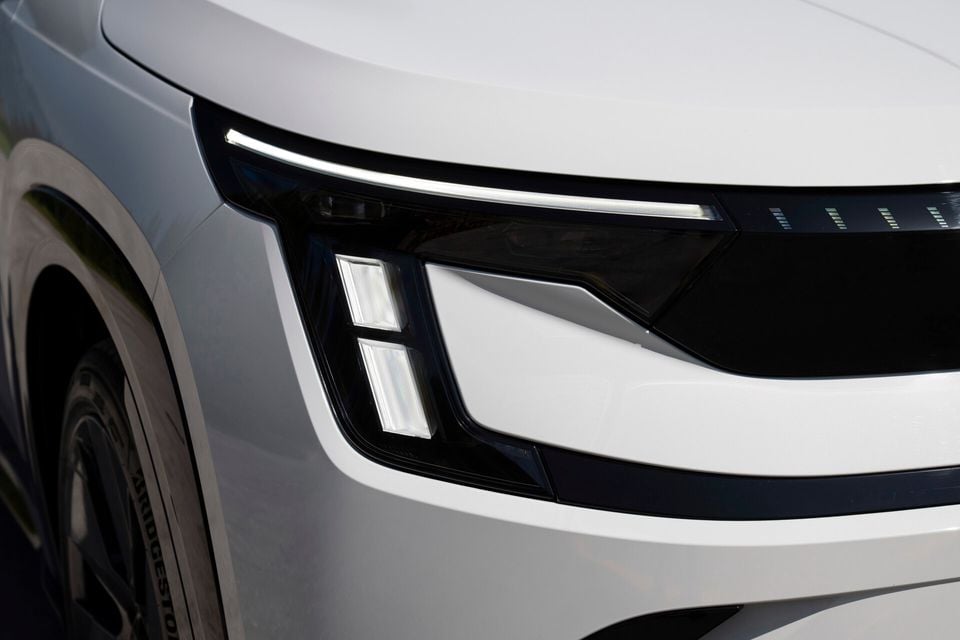 Close-up of the LED headlight on a white Skoda Peaq SUV, showing angular daytime running lights and stacked light modules