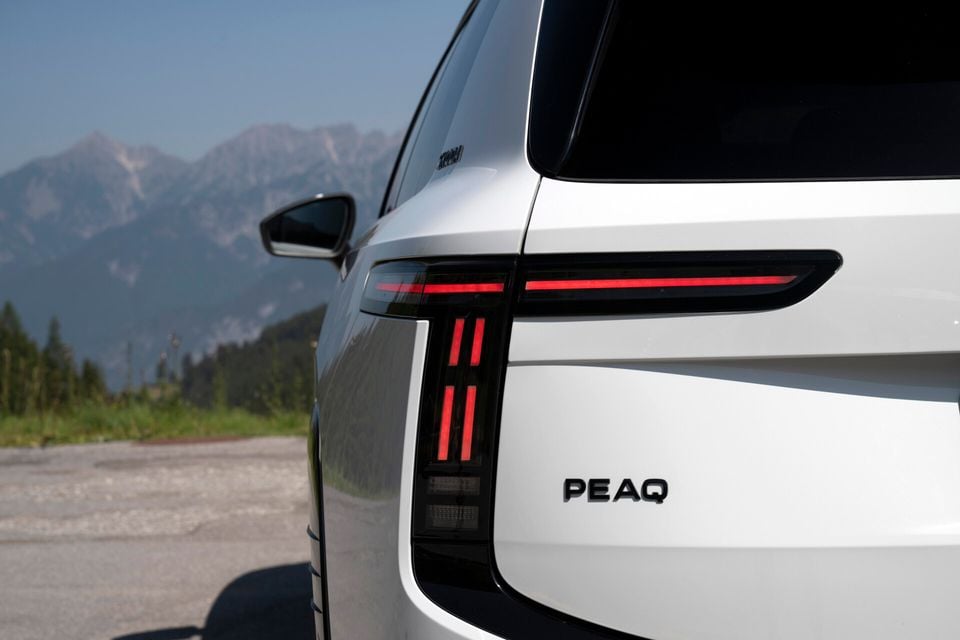 Close-up of the rear tail light and PEAQ badge on a white Skoda Peaq SUV, with mountains in the background
