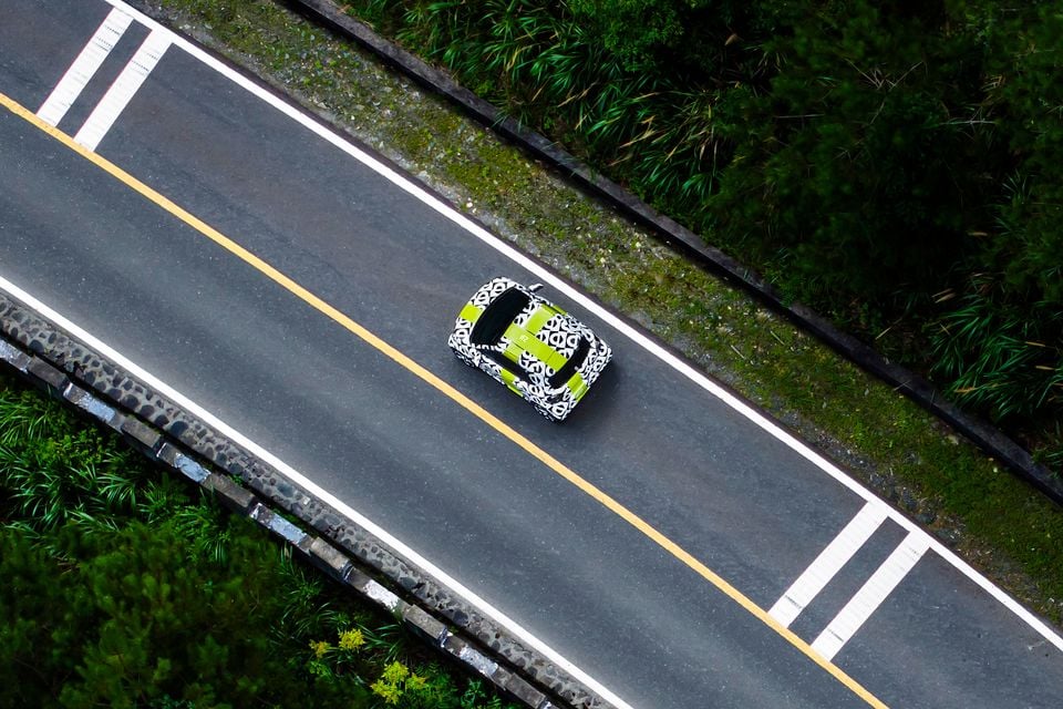 A camouflaged smart #2 prototype seen from above driving on a road, featuring green and black-and-white wrap