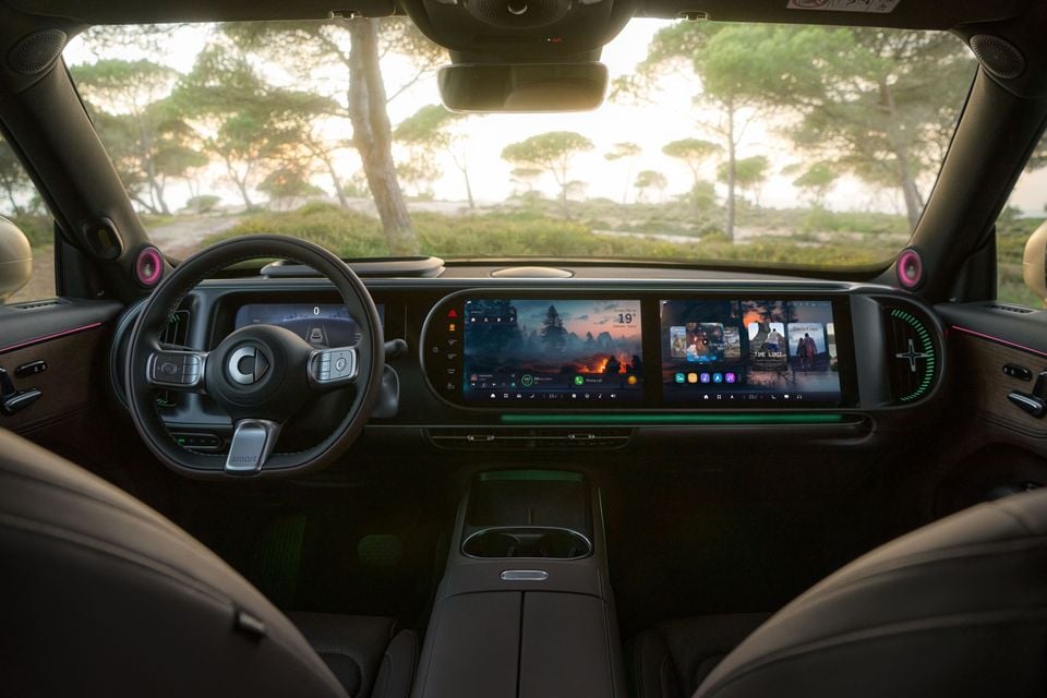 Interior dashboard view of a Smart #5 showing a wide dual touchscreen infotainment display, steering wheel with Smart logo, and ambient lighting