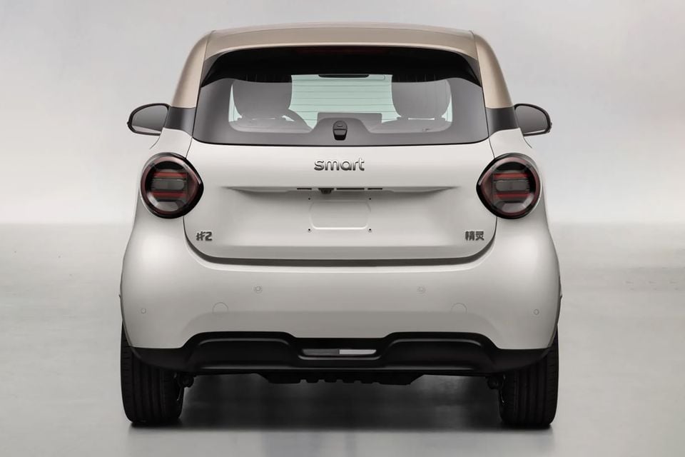 Rear view of a Smart Hashtag 2 small hatchback in white with a gold roof, shown in a studio setting