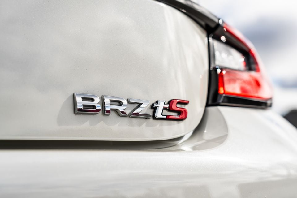 Close-up of the BRZ tS badge on the rear of a white Subaru BRZ tS, with a tail light visible in the background.