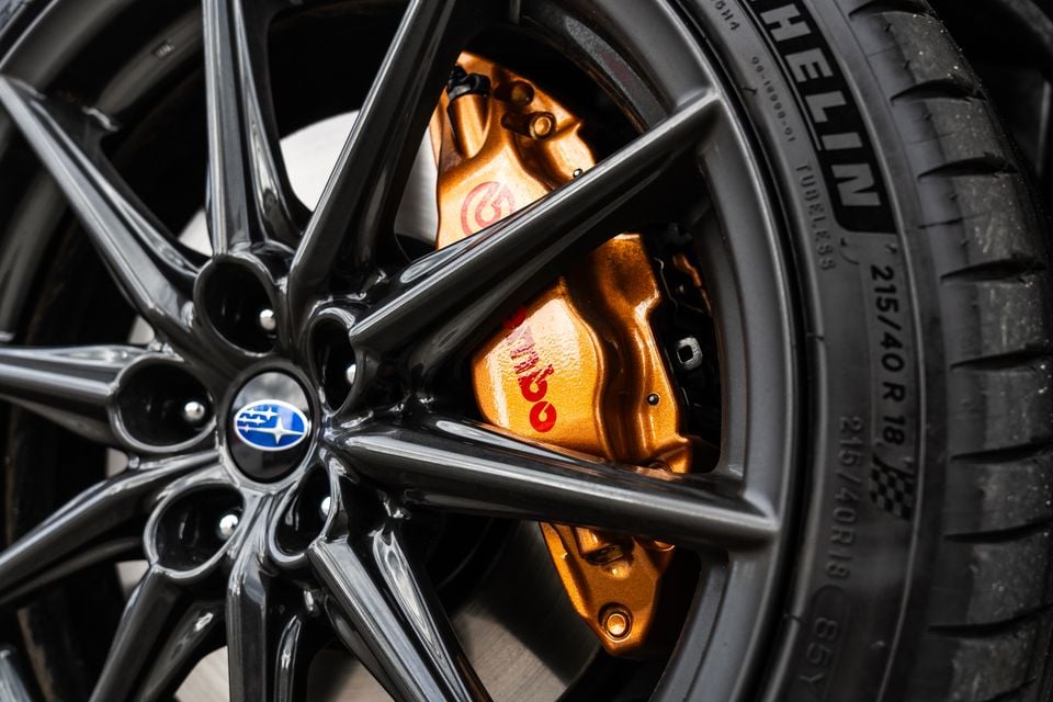 Close-up of a Subaru BRZ's dark alloy wheel showing a gold Brembo brake caliper and Michelin 215/40 R18 tyre