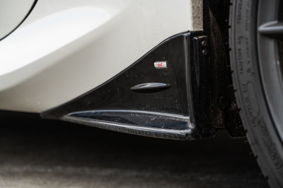 Close-up of the STI badge and side skirt splitter detail on a white Subaru BRZ tS near the front wheel