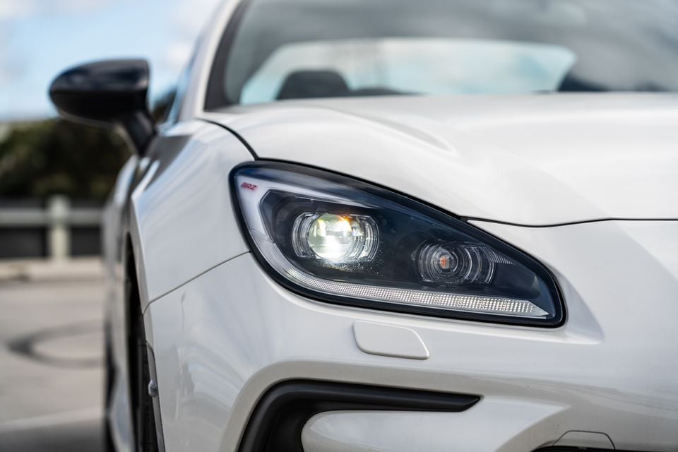 Close-up of the LED headlight on a white Subaru BRZ, with the BRZ badge visible near the headlight housing