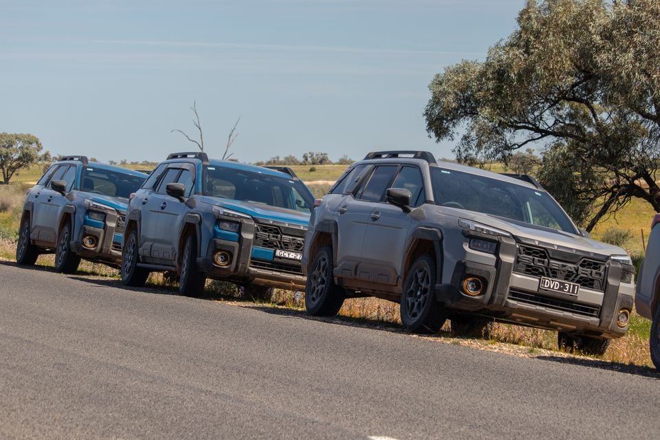Multiple Subaru Outback Wilderness SUVs parked along a rural road in outback Australia, seen from the front and side in grey and blue colours