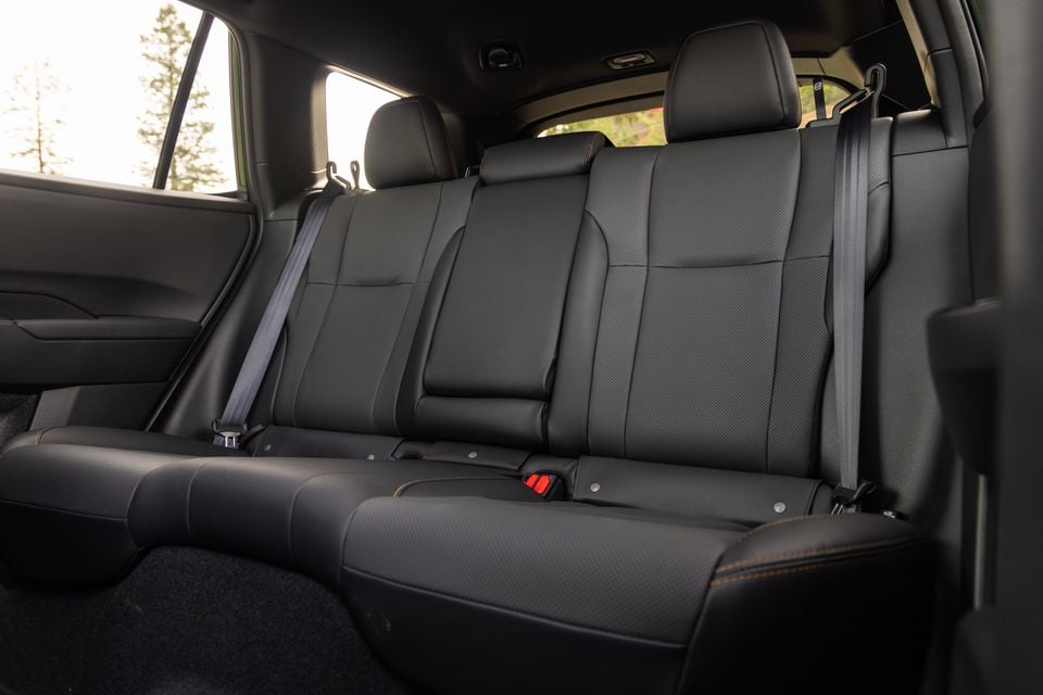 Rear seat interior of a 2027 Subaru Outback Wilderness, showing black leather bench seating with orange stitching and seatbelts