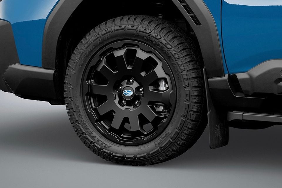 Close-up of a black 18-inch alloy wheel with all-terrain tyre on a blue Subaru Outback Wilderness