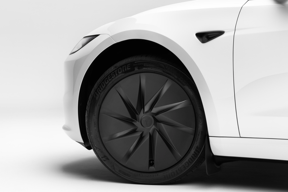 Close-up of a white Tesla Model 3's front wheel showing its dark aerodynamic alloy rim and Bridgestone tyre.