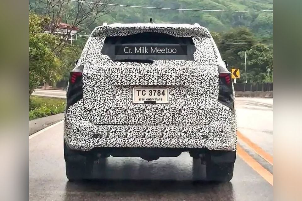 A camouflaged 2027 Toyota Fortuner prototype SUV seen from the rear driving on a wet road in Thailand