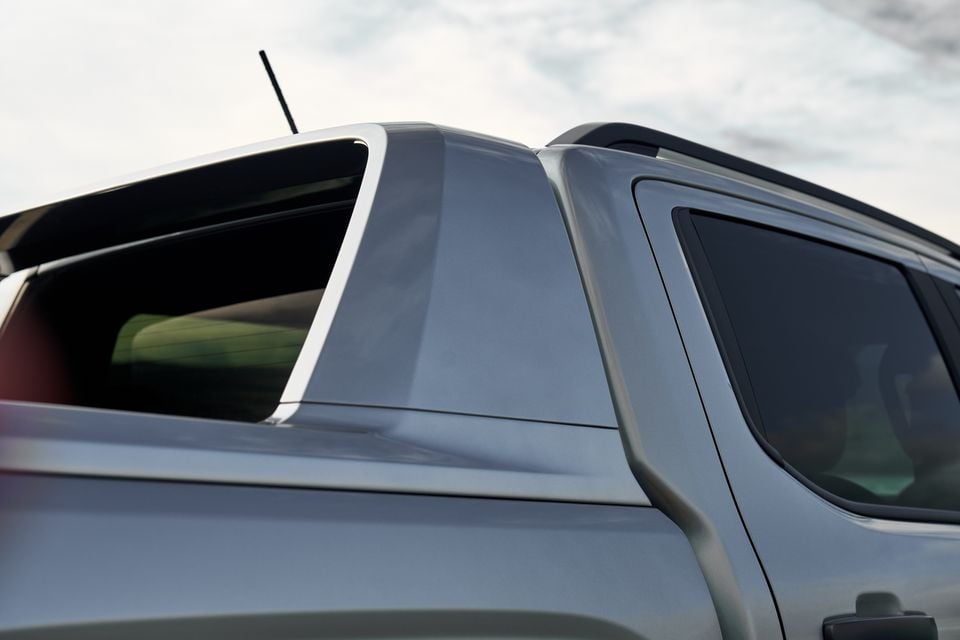 Close-up of the roofline, C-pillar and rear windows of a silver Volkswagen Amarok W600 by Walkinshaw, showing roof rails and tinted glass against a cloudy sky
