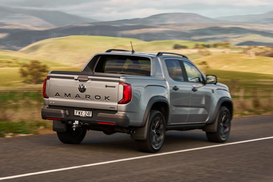 A silver Volkswagen Amarok V6 dual-cab ute seen from the rear while driving on a country road with rolling hills in the background