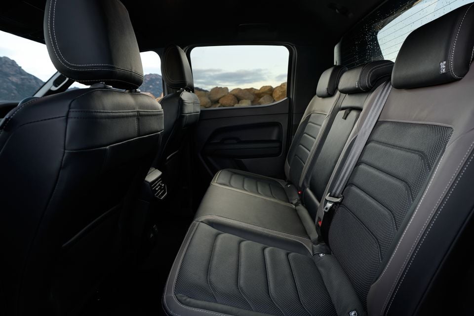 Rear seat interior of a Volkswagen Amarok W600 by Walkinshaw, showing black leather and fabric upholstery with white contrast stitching and seatbelts visible