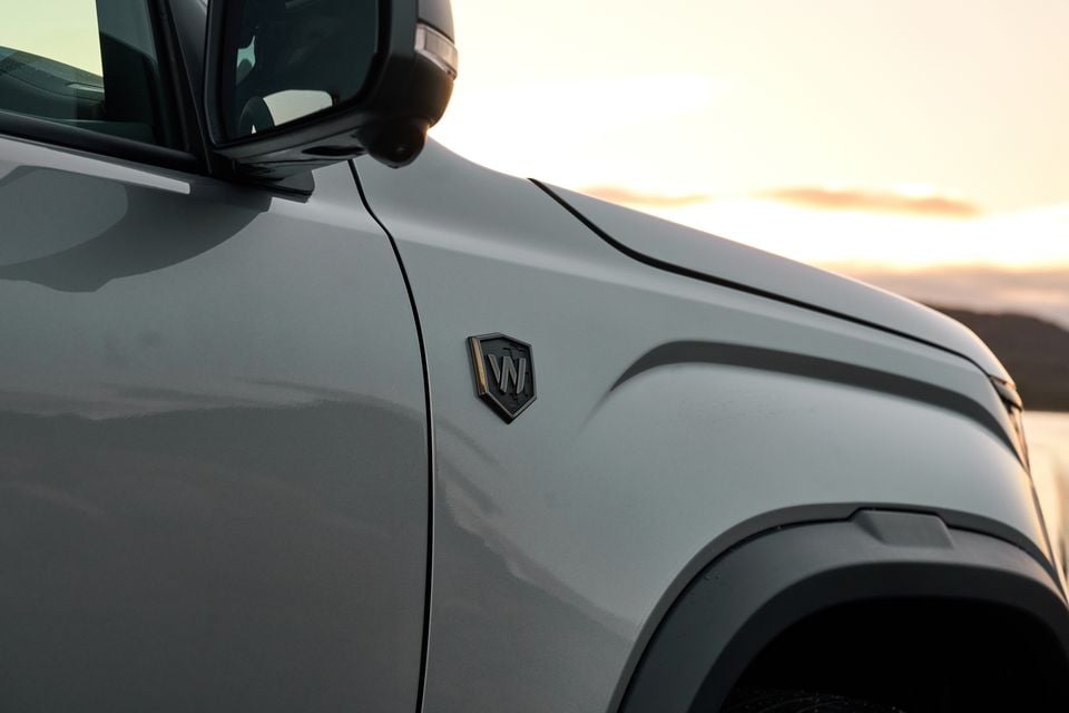 Close-up of the W600 Walkinshaw shield badge on the front guard of a white 2027 Volkswagen Amarok, shot at sunset