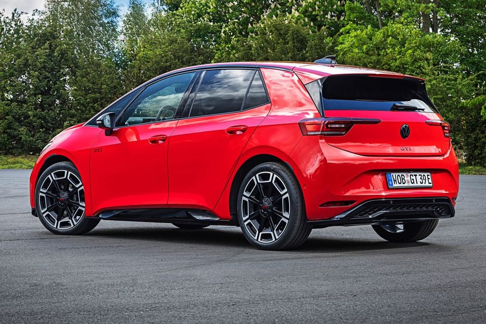 A red Volkswagen ID.3 GTI hatchback seen from the rear three-quarter angle, parked on a flat surface with trees in the background.