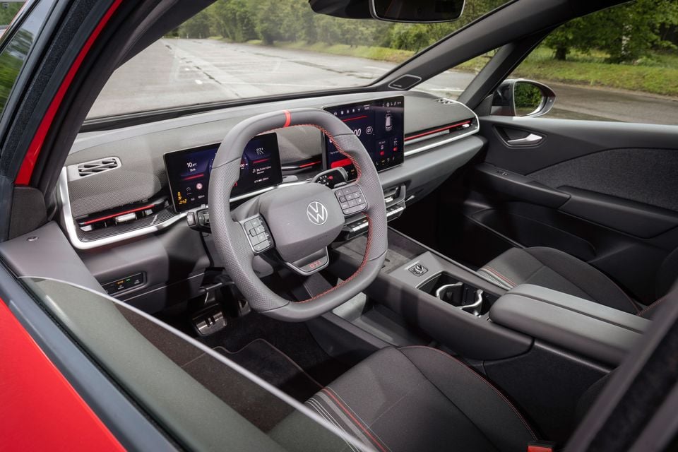 Interior of a Volkswagen ID.3 GTI showing the flat-bottomed GTI steering wheel with red stitching, dual digital screens, and sport seats with red accents