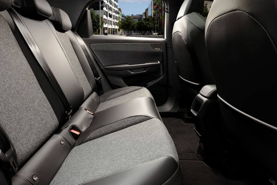The rear seat interior of a Volkswagen ID. Polo, showing grey fabric and black leather upholstery with seatbelts and door trim visible