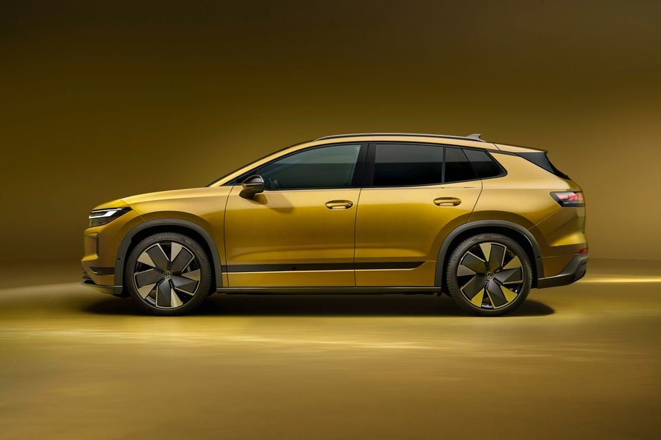 A gold 2027 Volkswagen ID. Tiguan electric SUV shown in side profile in a studio