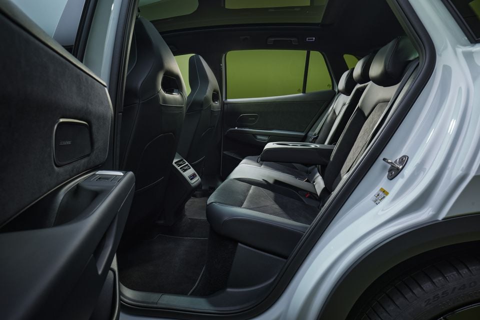 Rear seats of the 2027 Volkswagen ID. Tiguan seen through the open rear door, showing black leather and suede upholstery and a fold-down armrest