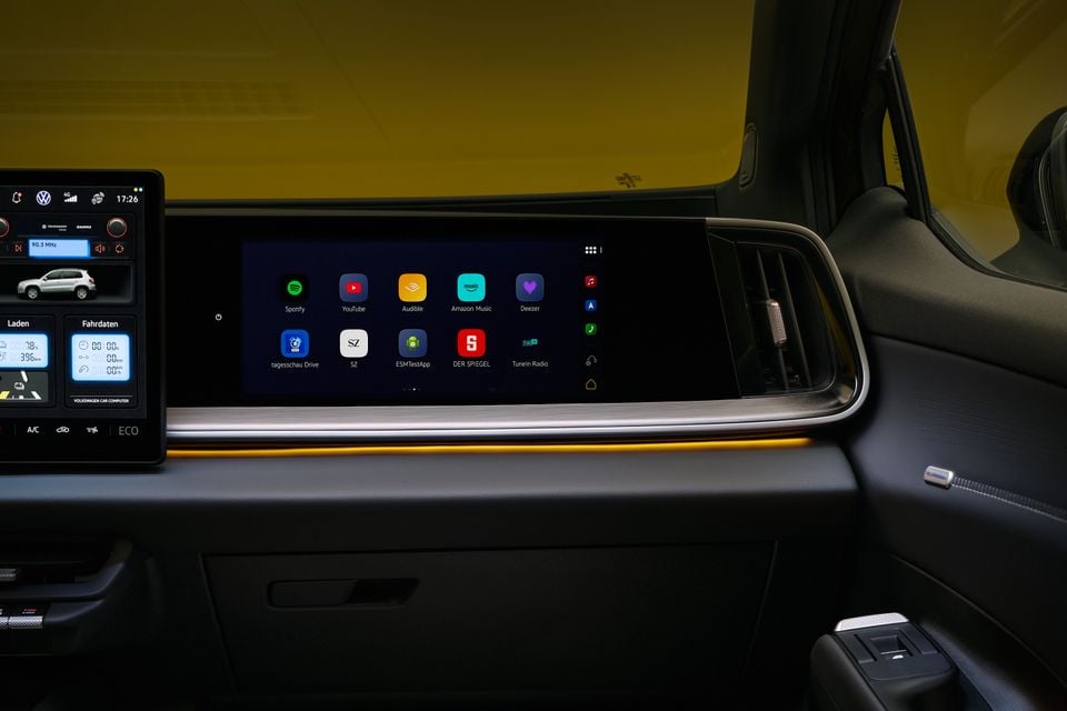 Dashboard of the 2027 Volkswagen ID. Tiguan showing a passenger-side touchscreen with streaming app icons and a retro-styled central infotainment display