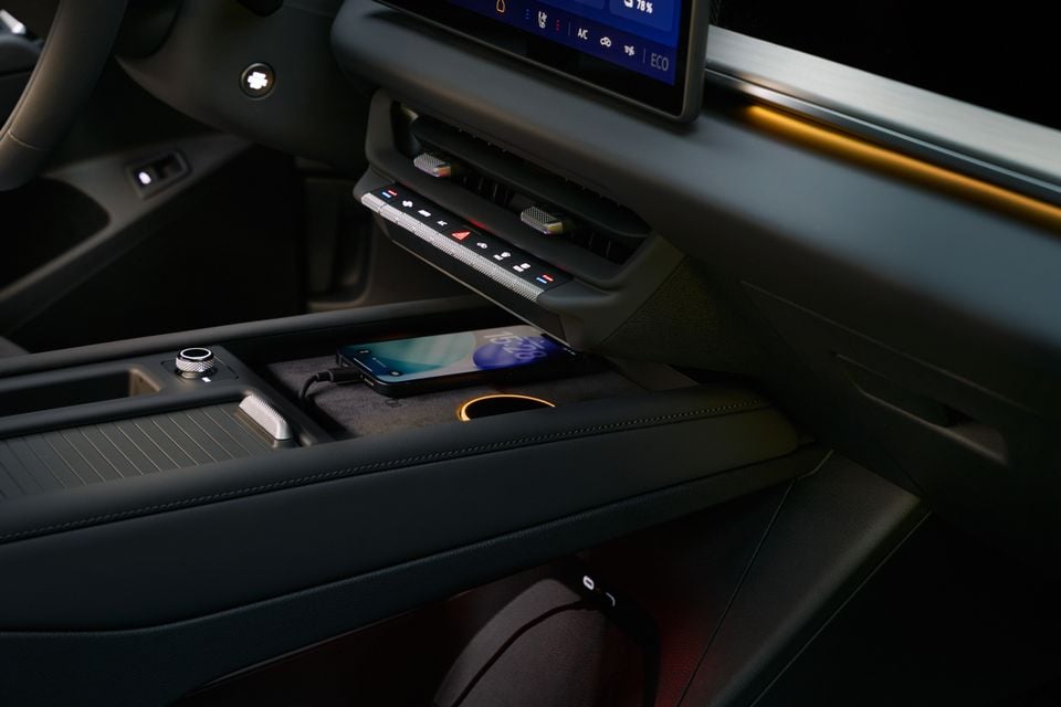 Centre console of the 2027 Volkswagen ID. Tiguan with a smartphone on the wireless charging pad, climate control buttons and touchscreen above
