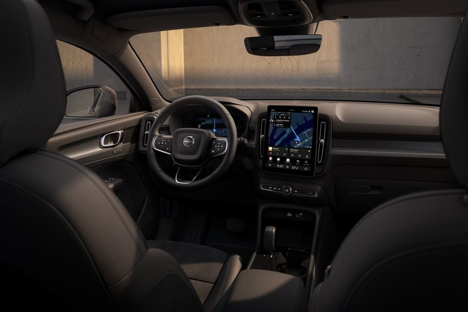 Interior of a Volvo EX40 or XC40 showing the dashboard, steering wheel, and large central touchscreen displaying a map