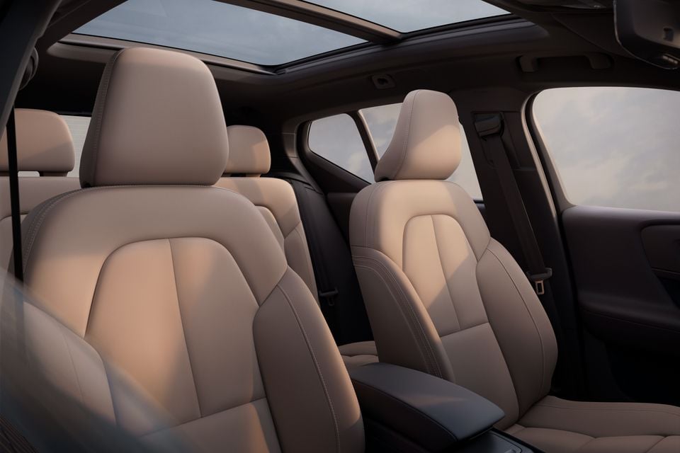 Beige leather front and rear seats inside a Volvo SUV, with a panoramic sunroof overhead