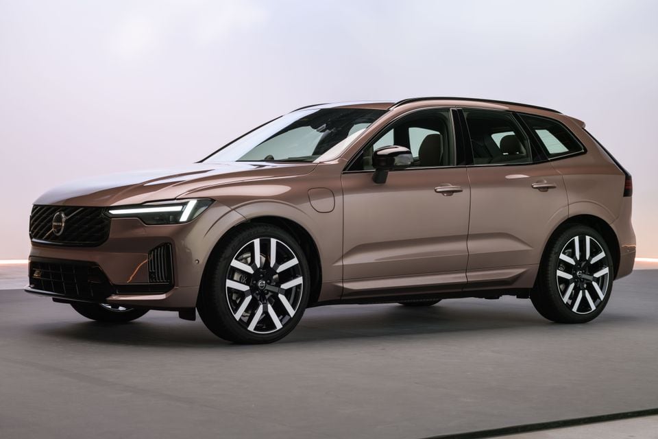 A bronze/tan 2027 Volvo XC60 SUV seen from the front-side angle in a studio setting