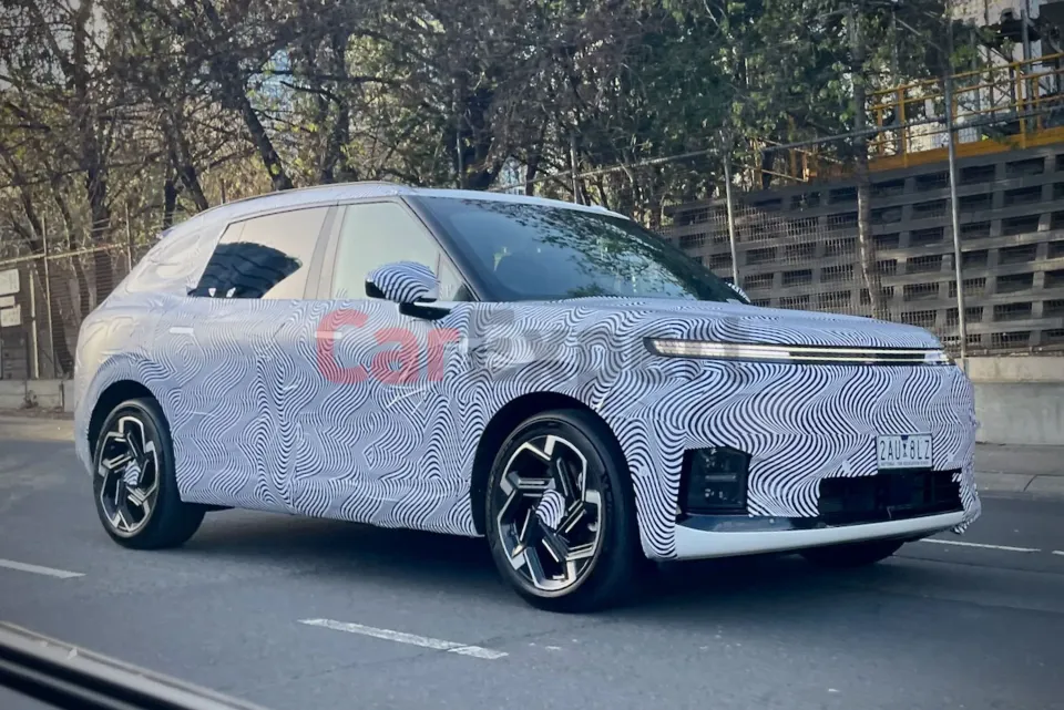 A camouflage-wrapped prototype of a Xpeng SUV, likely the next-generation G9, photographed on a suburban road during testing.