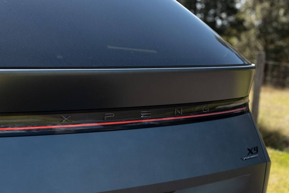 Close-up of the rear of a dark grey XPENG X9 Performance, showing the full-width light bar and model badge