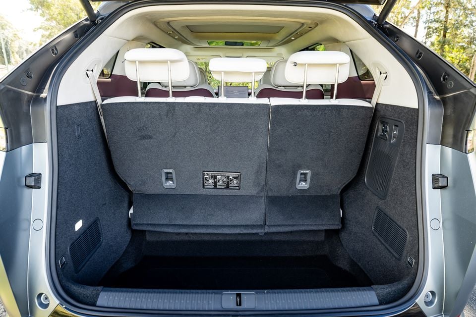 The boot of an XPENG X9 SUV open, showing a large carpeted cargo area with rear seat headrests and a two-tone white and burgundy interior visible beyond.