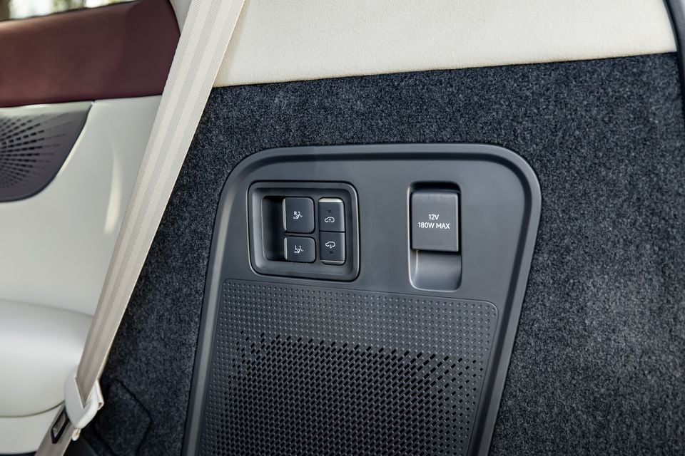 Interior panel of the 2027 Xpeng X9 showing seat adjustment controls, a 12V 180W max power outlet, and a speaker grille on the rear quarter panel