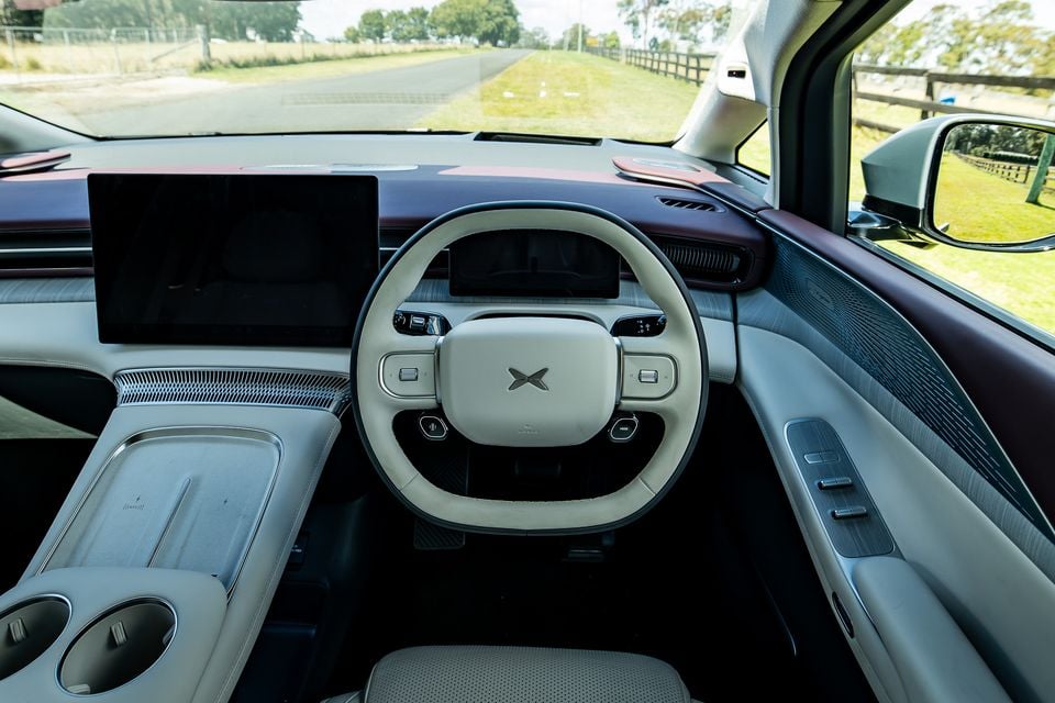 Interior of the 2027 Xpeng X9 showing the steering wheel, large central touchscreen, digital instrument cluster, and light-coloured cabin trim