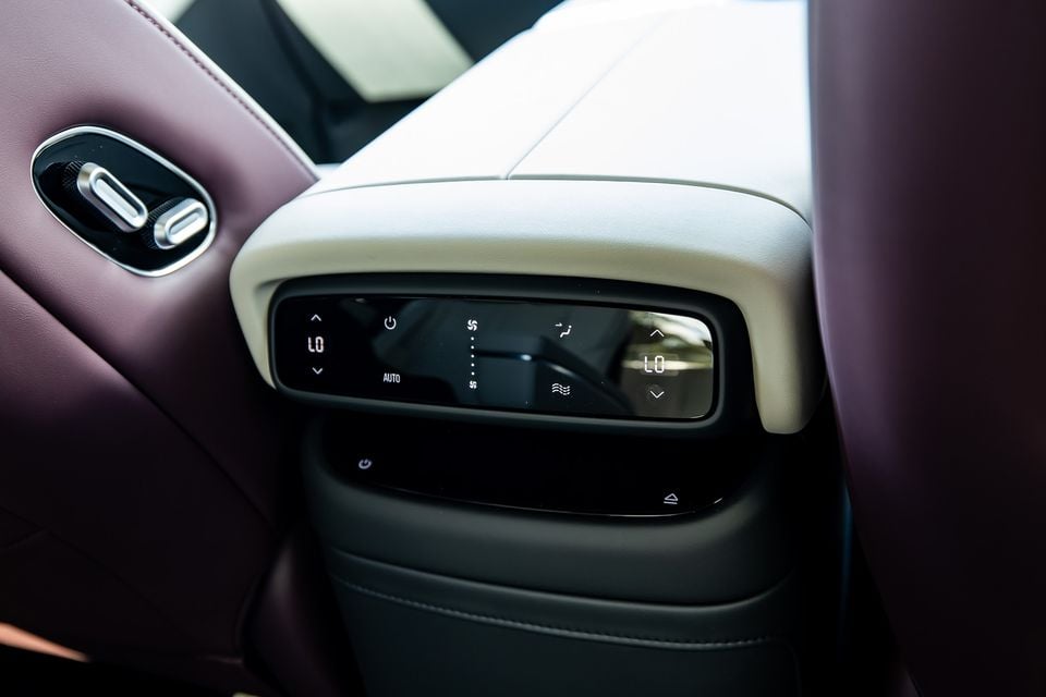Rear seat climate control panel with touch controls in a luxury car interior featuring two-tone leather upholstery