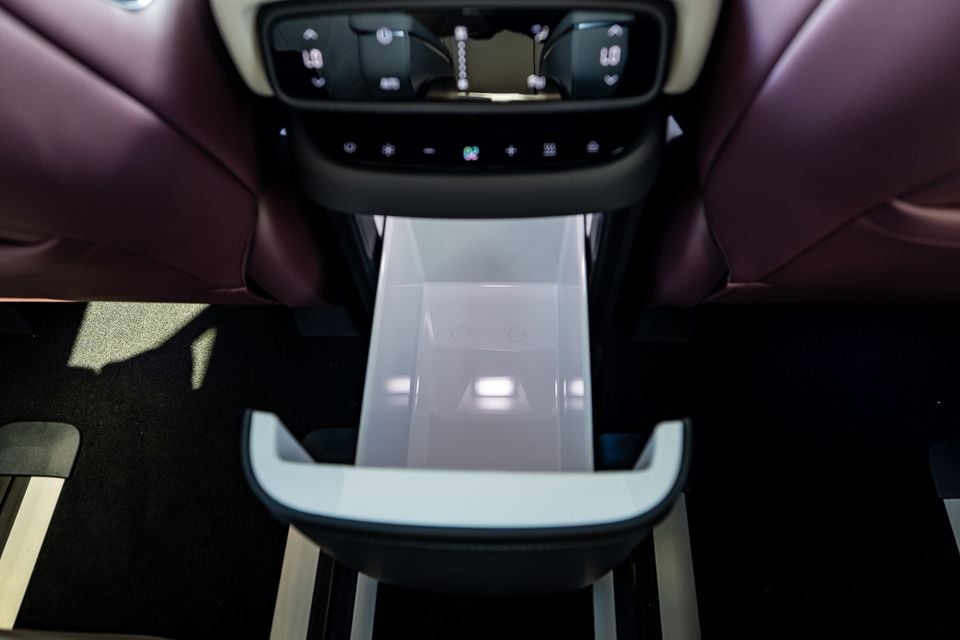 Open storage compartment in the centre console of an XPENG X9, with rear climate controls visible and burgundy leather seating on either side