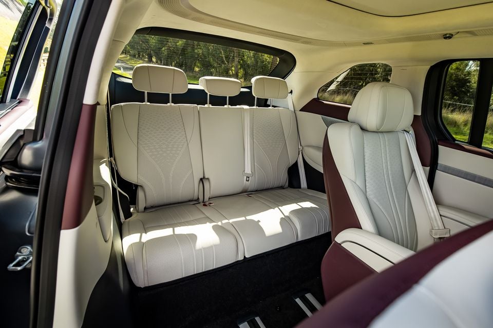 The third-row bench seat and second-row seat of the 2027 Xpeng X9, trimmed in light grey and burgundy leather