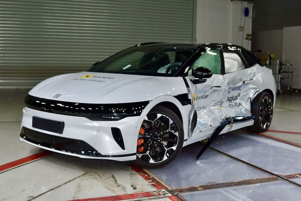 A white Zeekr 7GT undergoes a side-impact crash test, showing crumple damage to the driver's side door, with Euro NCAP markings visible in a testing facility.